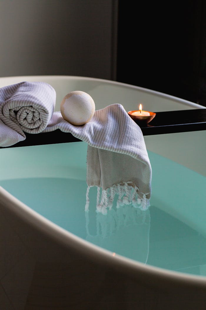 Home Elegant indoor spa setting with bathtub, candle, towel, and bath bomb for relaxation.