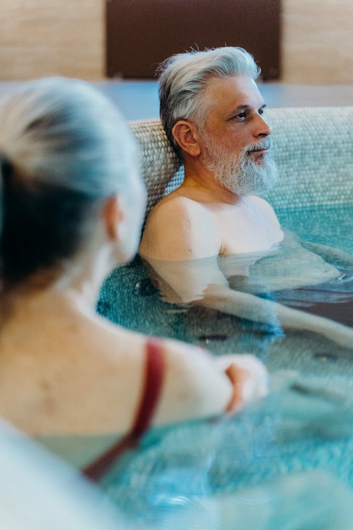 Home Two senior adults enjoying a relaxing moment in a spa pool, emphasizing leisure and tranquility.