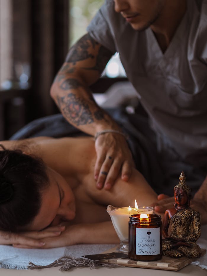 Home Tattooed massage therapist providing a relaxing spa treatment with candles for ambiance.